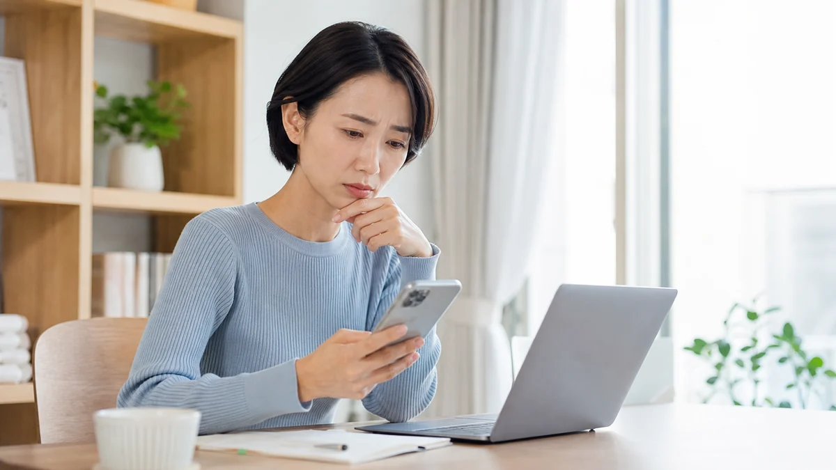 パスワード再発行メールが届かずスマートフォンを確認する女性