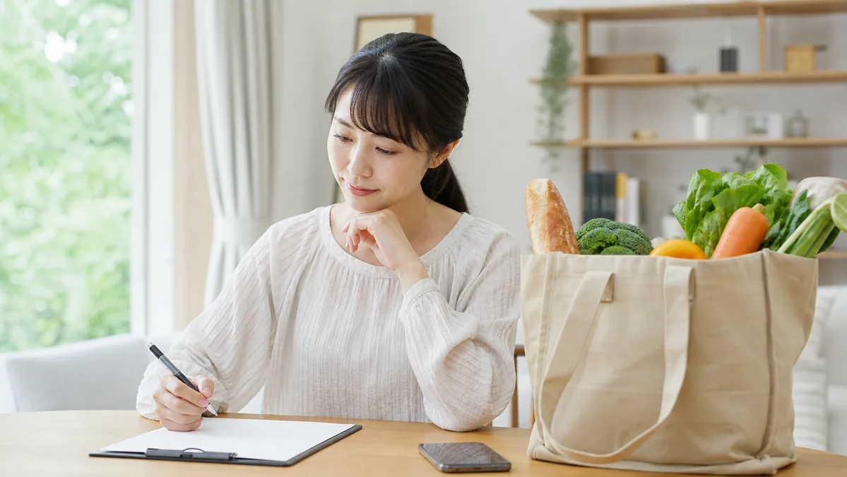 買い物袋の横で参加条件を比較する女性