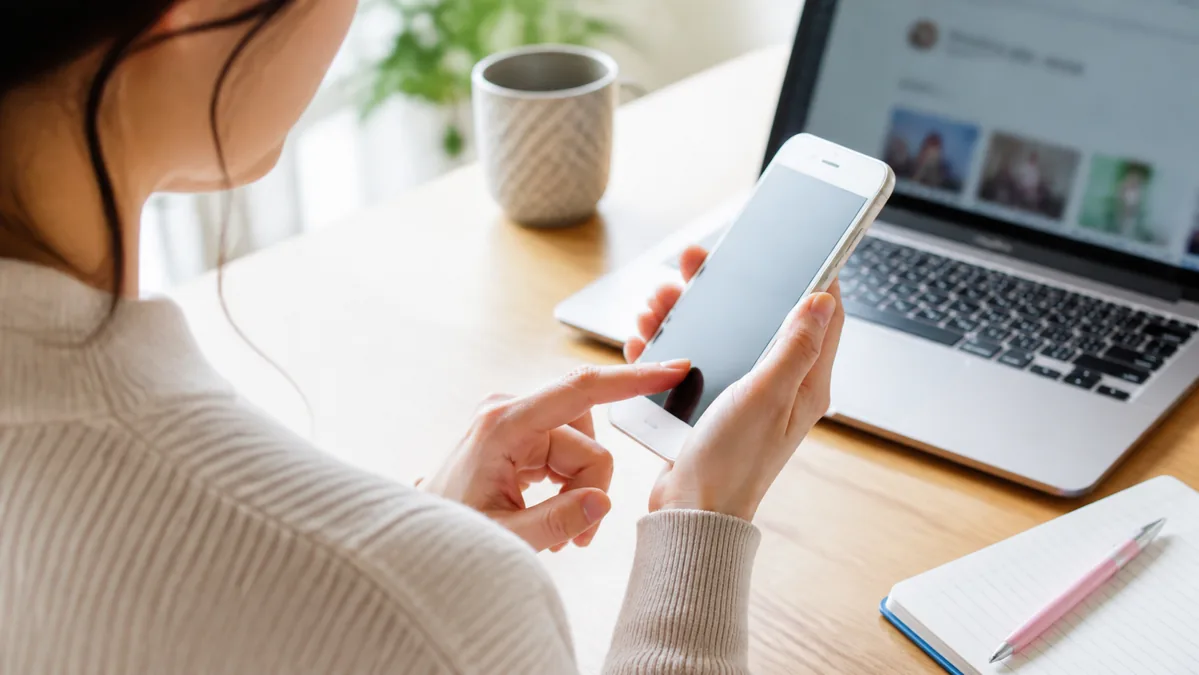 スマートフォンで紹介方法を確認する女性の手元